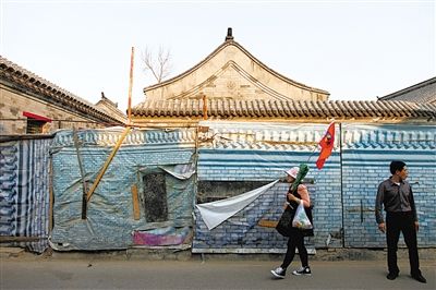 昨日，小石碑胡同，一位導遊帶著遊客走過建築圍擋。西城區今年計劃啟動什剎海舊城保護示范項目。新京報記者